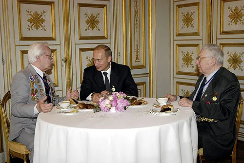 Vladimir Poutine avec les vétérans russes de Normandie Gleb Plaksine et Oleg Ozerov. Caen, 6 juin 2004 — le jour même où il remit à Andreï Schmemann son passeport russe. Photo : Kremlin.ru (Wikimedia Commons, CC BY 4.0).

