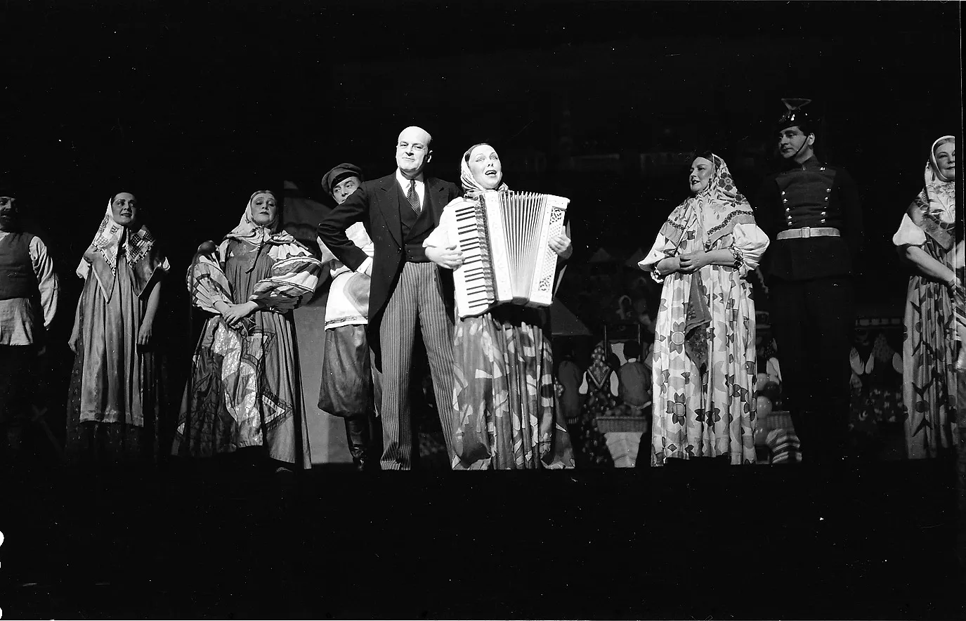 Le cabaret L&rsquo;Oiseau bleu (Der blaue Vogel) sur scène : au centre, en costume, son fondateur et compère Iakov Ioujny, à côté de lui une artiste à l&rsquo;accordéon. Le Berlin russe qui survécut à Charlottengrad. Photo : Staatsarchiv Freiburg, LABW (CC BY 4.0).
