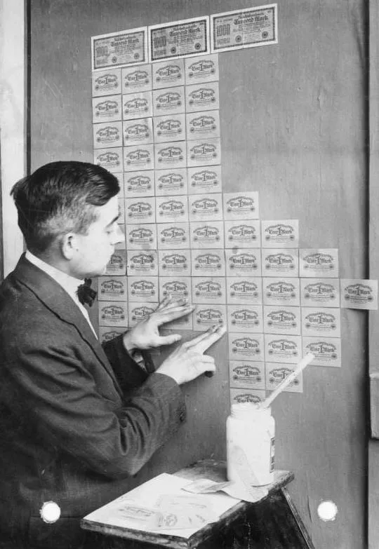 Berlin, 1923 : on tapisse un mur de billets dévalués comme de papier peint. Le Berlin russe « vivait sur la différence des cours » — sur le bon marché que donnait l&rsquo;hyperinflation. Photo : Georg Pahl, Bundesarchiv Bild 102-00104 (CC BY-SA 3.0 de).